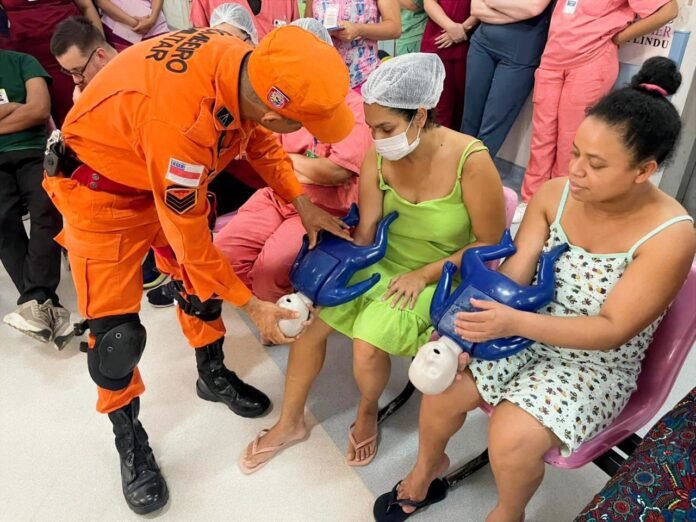 Dona Lindu realiza treinamento de desengasgo em recém-nascidos para mães em Manaus durante a Semana das Mães com apoio do Corpo de Bombeiros.